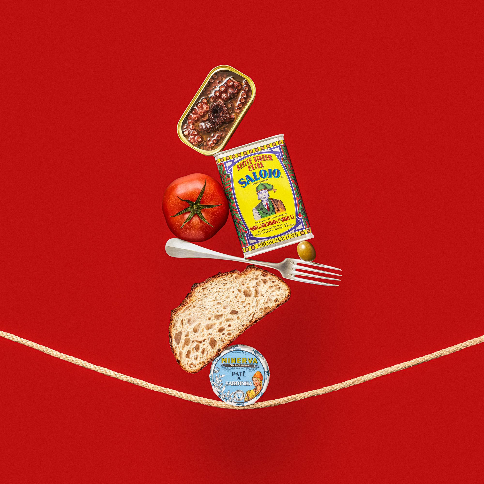 pate, a slice of bread, fork, olive, olive oil, tomato, and a can of octopus balancing on a string